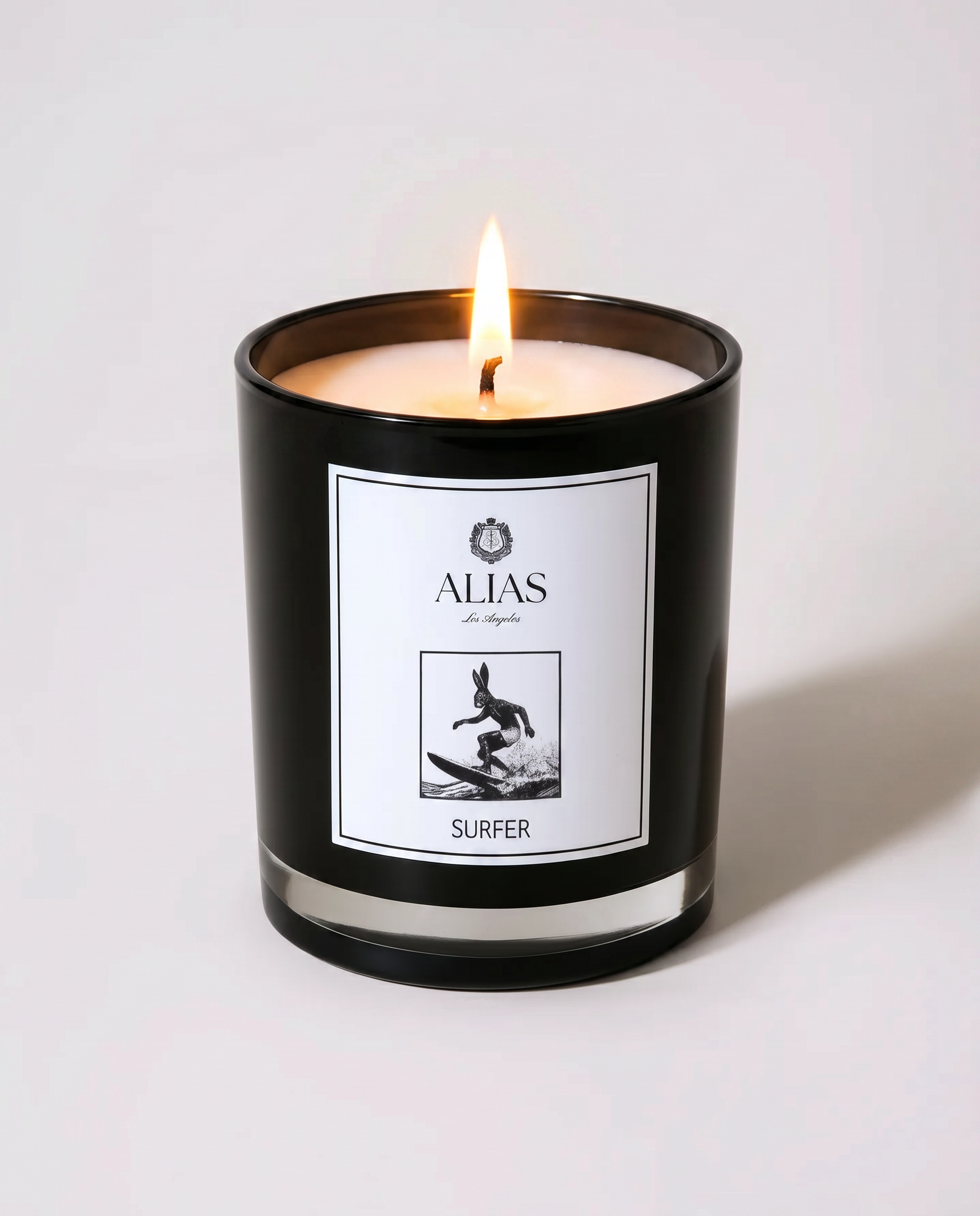 The Surfer luxury candle by Alias Los Angeles – glossy black jar with a fresh coastal fragrance of sea spray, koa wood, and ylang ylang; a soy wax candle inspired by California beach lifestyle, perfect for summer home décor, beach house ambiance, and thoughtful gifting.