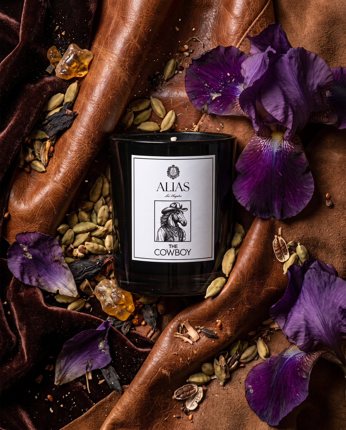 The Cowboy candle by Alias Los Angeles in a shiny black vessel, surrounded by its fragrance notes of santal, leather, and iris flower.